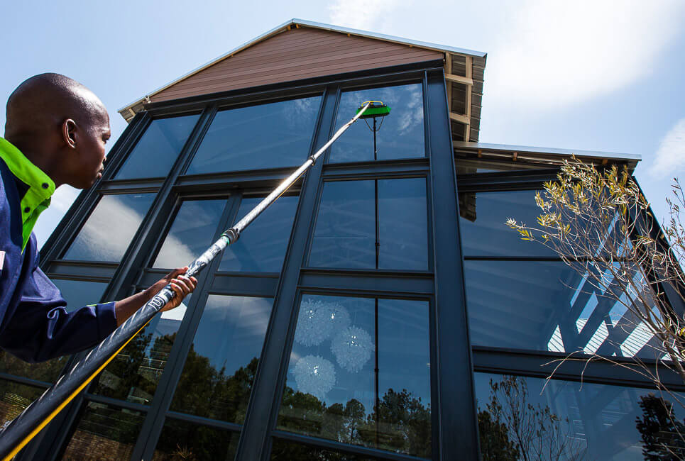 Photo of a man operating a water fed pole cleaning commerical windows
