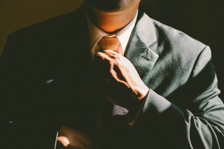Photo of business man in a suit adjusting his tie